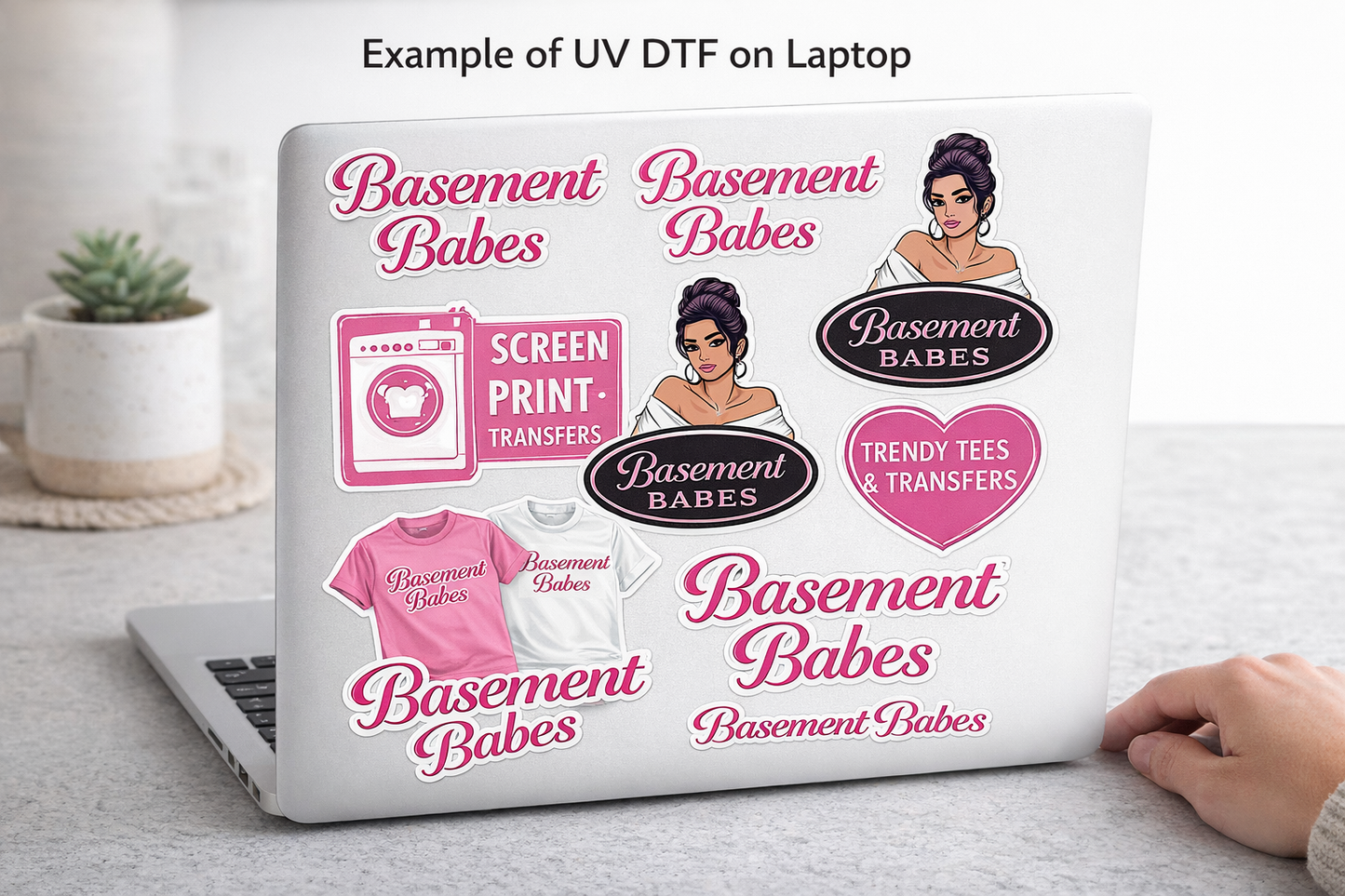 Laptop with 'Basement Babes' branding and graphics on a light background