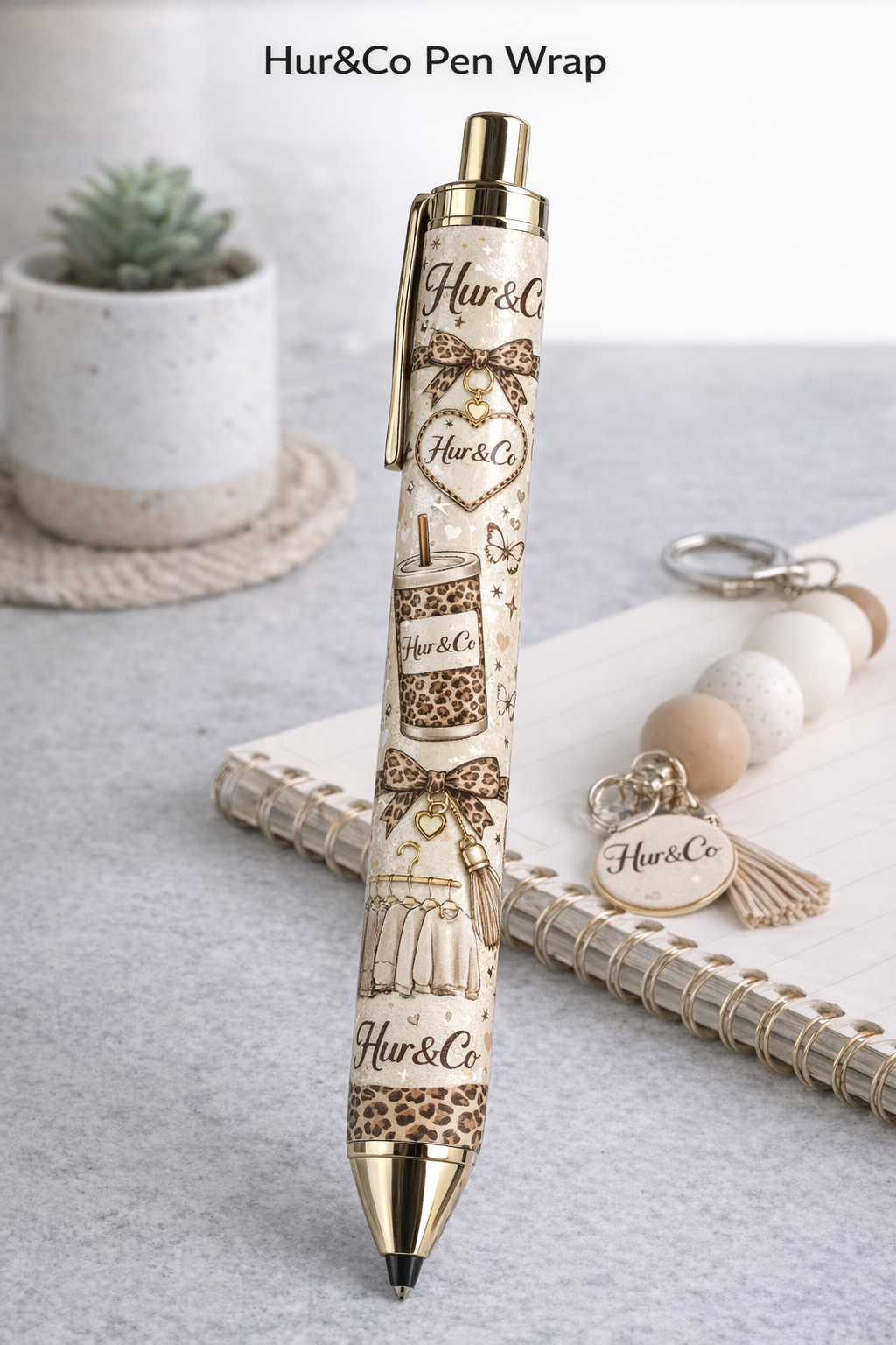 Pen with 'Hur&Co' branding on a light surface with a notebook and keychain.