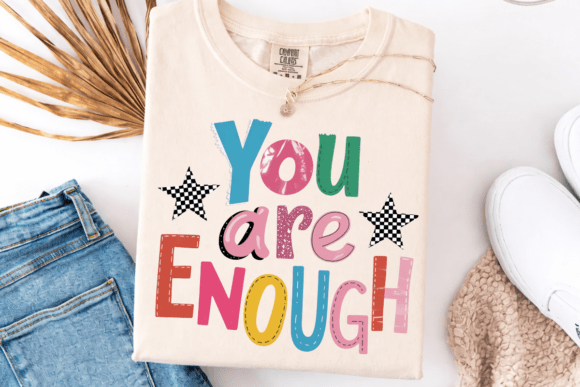Beige sweatshirt with 'You are Enough' text on a white surface with jeans and shoes.